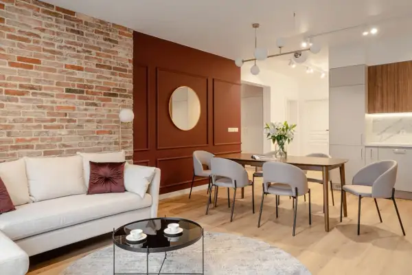 Nowoczesny salon z ceglaną ścianą i elegancką, bordową ścianą. Idealne pytanie: jaki kolor ścian do cegły? Tutaj bordowy świetnie się sprawdza.